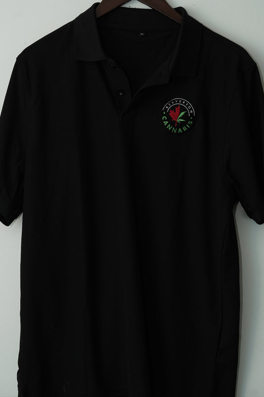 Black polo shirt with a logo on a hanger against a white wall