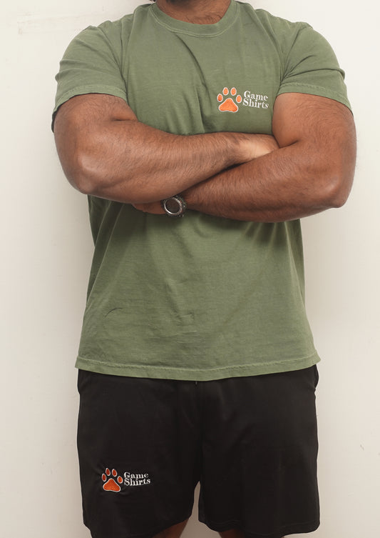 Person wearing a green t-shirt and black shorts with 'Game Shirts' logo on a white background