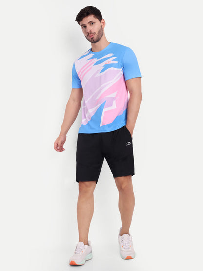 Man wearing a blue and pink abstract patterned t-shirt with black shorts on a white background