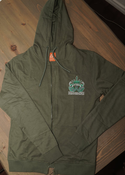 An olive green zip-up hoodie laid flat on a wooden table, featuring a small graphic on the left chest \
