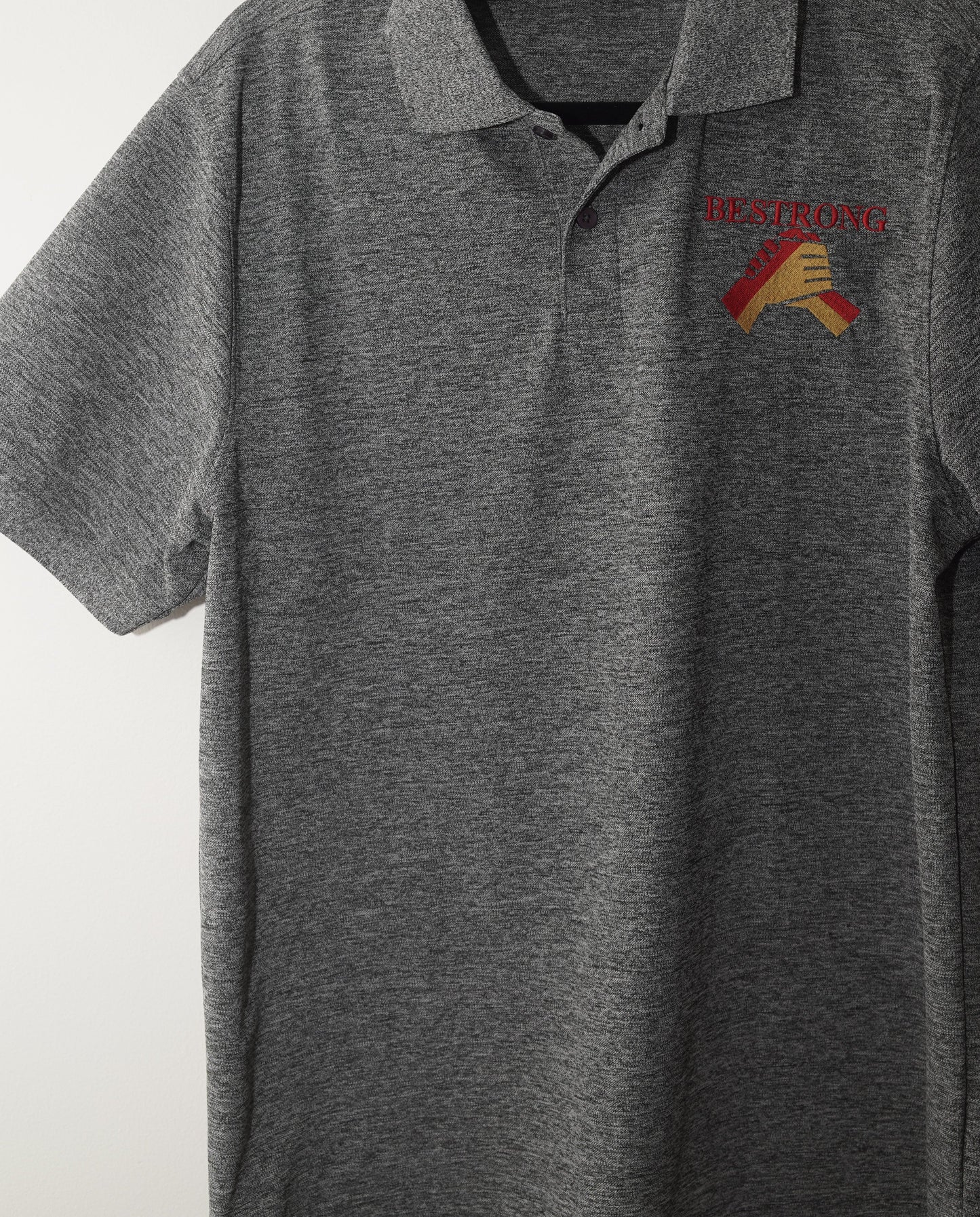 A gray heathered long-sleeve polo shirt with a small embroidered logo on the left chest, hanging on a white wall.