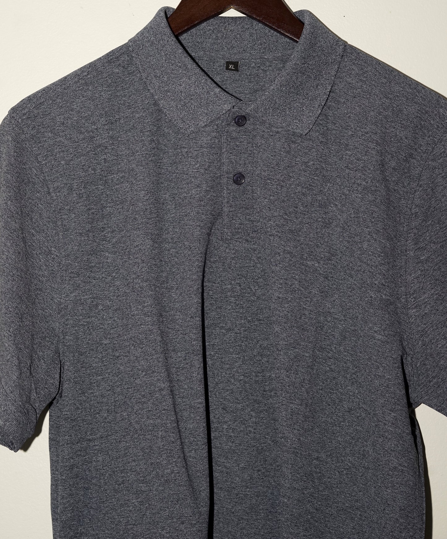 Gray navy blue polo shirt on a hanger against a plain background