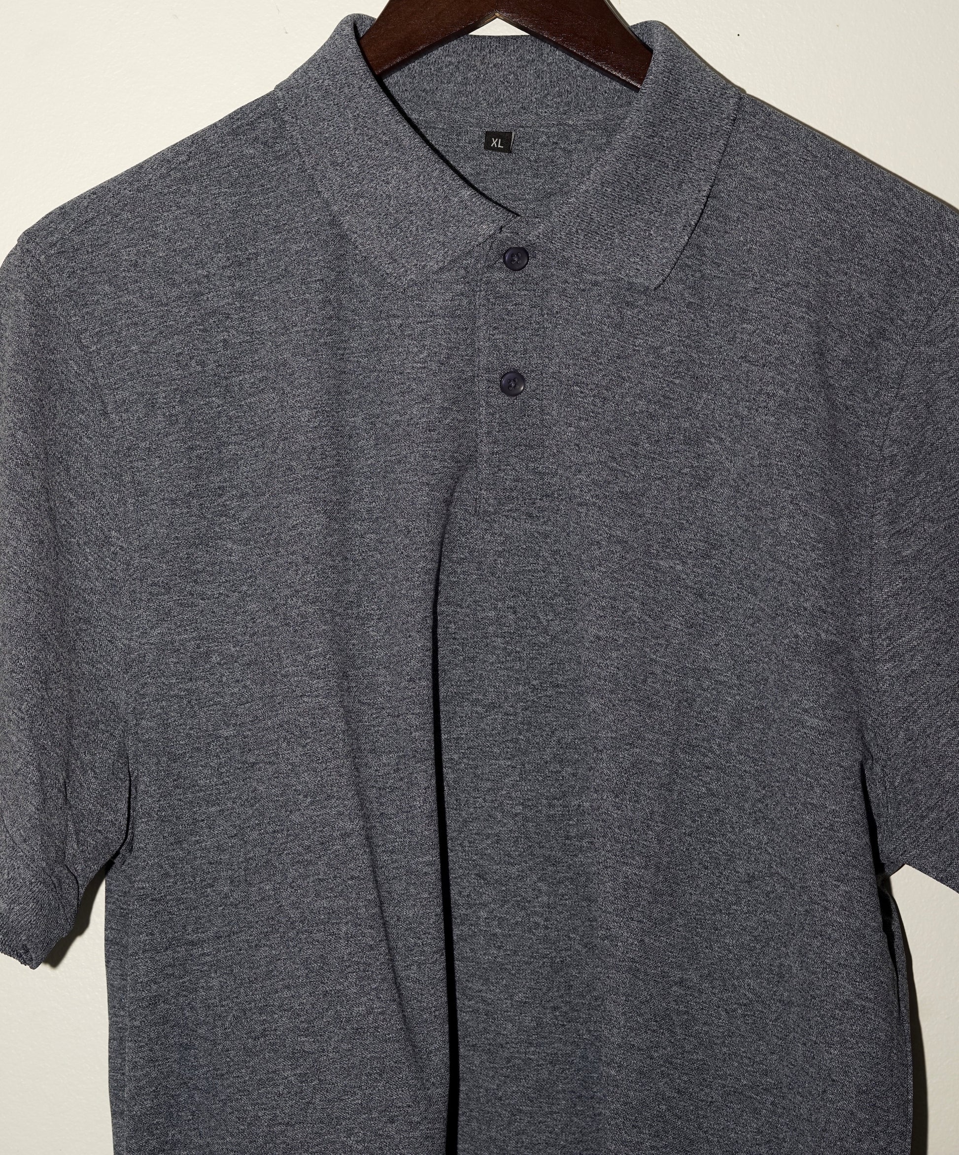 Gray navy blue polo shirt on a hanger against a plain background