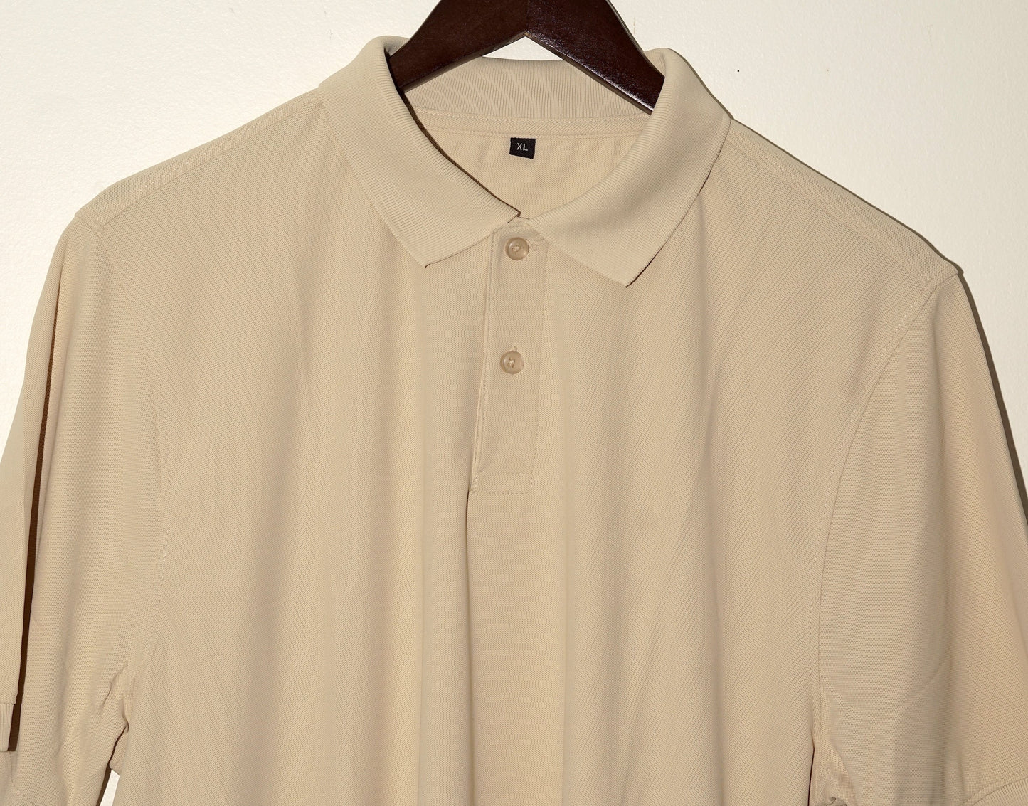 Beige polo shirt on a hanger against a white background