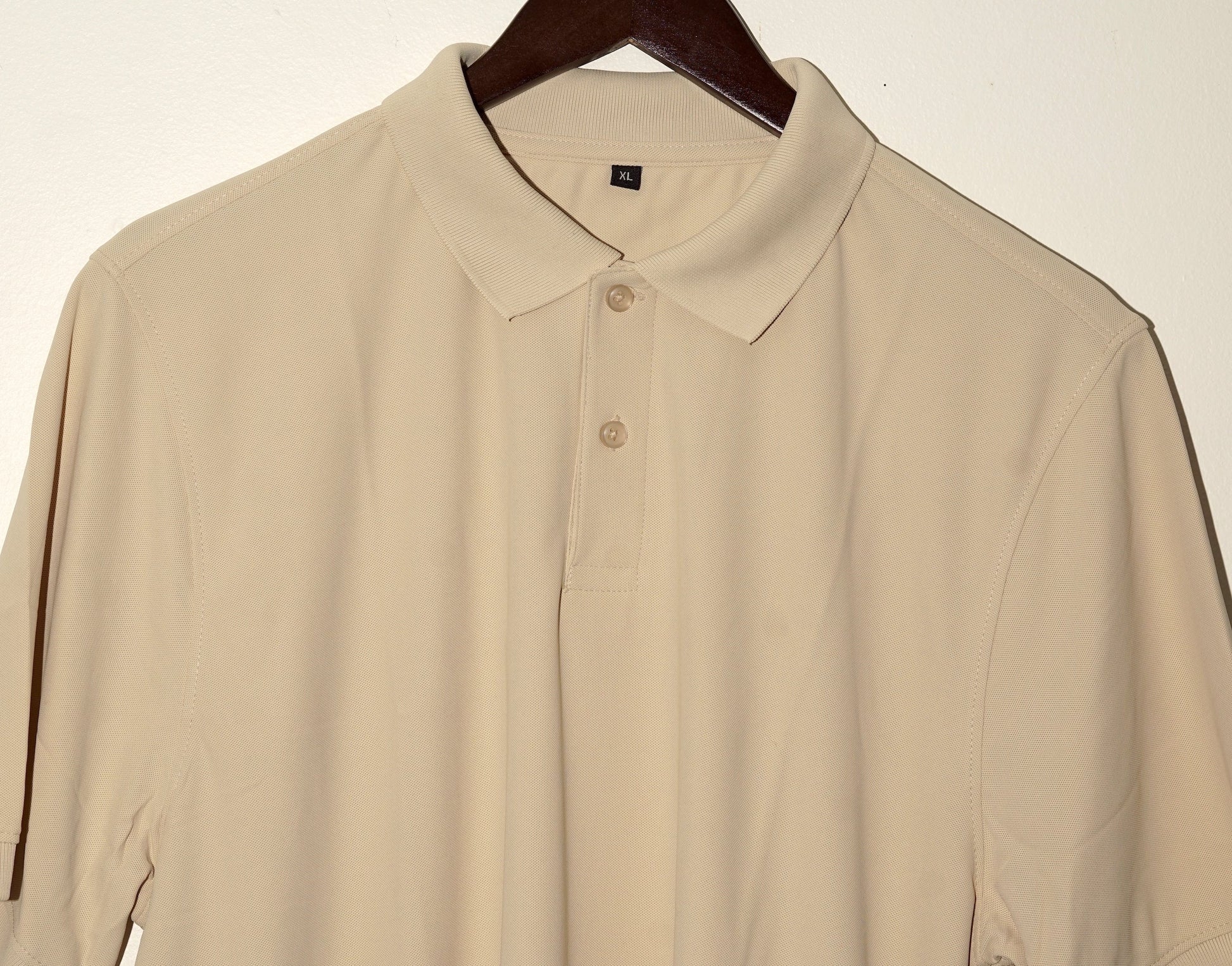 Beige polo shirt on a hanger against a white background
