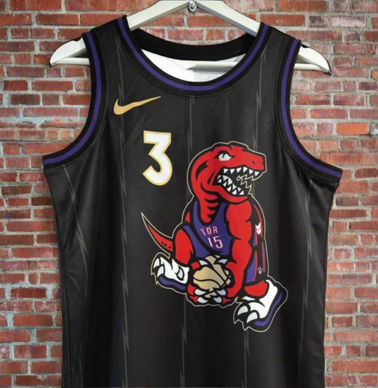 Black basketball jersey with a dinosaur graphic on a hanger against a brick wall.